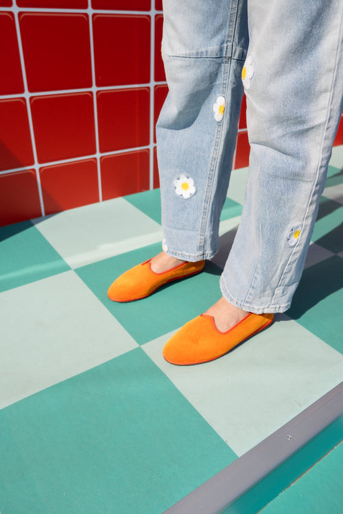 Tradizionale Arancio orange velvet flats worn on a teal checkerboard floor